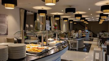 A buffet area with multiple food stations, a glass display case, and a seating area with tables and chairs.