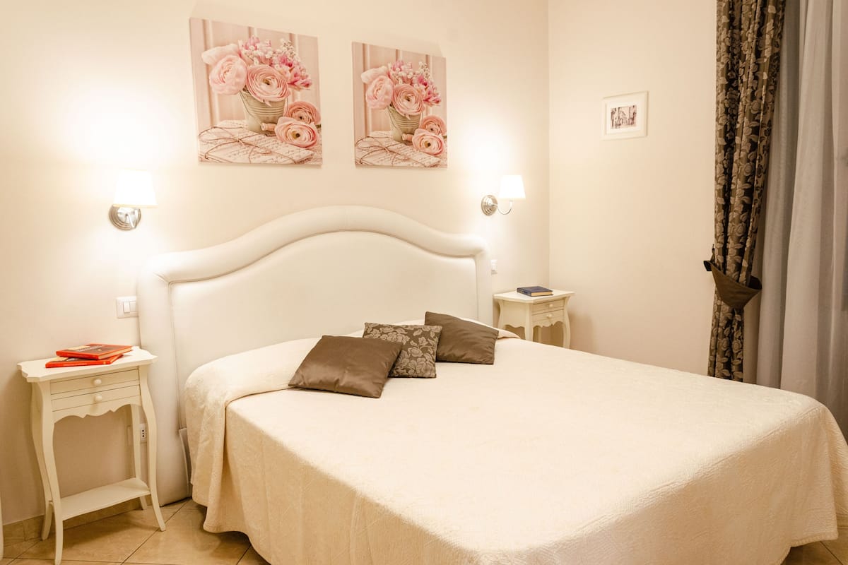 A neatly arranged bedroom with a large bed, two bedside tables, and wall-mounted lamps.