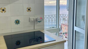 Une cuisine équipée d’une cuisinière moderne, d’une hotte aspirante et offrant une vue sur la mer depuis un balcon.