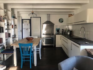 A compact kitchen with a dining table, chairs, a stove, and a sink.