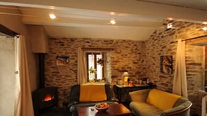 Una sala de estar acogedora con una pared de piedra, una chimenea, un sofá y una mesa de centro.