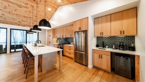 A modern kitchen with wooden cabinets, stainless steel appliances, and a large island with bar stools. - Luxury Mountain Retreat: Skiing, Hiking, Sauna (Tucker County)