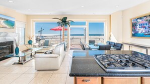 A spacious living area with a kitchen, large windows offering a view of the beach, and a dining area with a view of the ocean. - Oceanfront! Clean & Affordable Upstairs Split Level Unit (Newport Beach)
