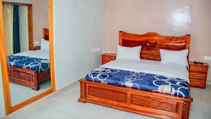 Une chambre à coucher avec un lit en bois, une table de chevet, un miroir et une commode.