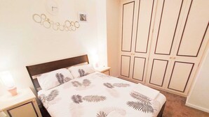 A bedroom with a bed, nightstands, a wardrobe, and a wall decoration.