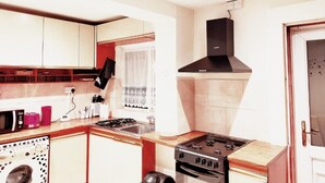 A compact kitchen with a gas stove, a microwave, and a washing machine.