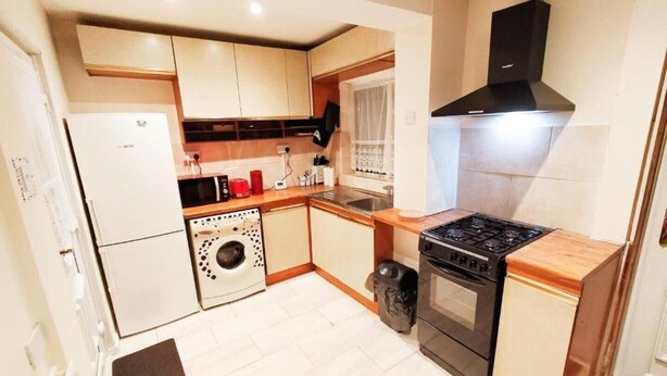 A compact kitchen with a washing machine, a stove, and a microwave.