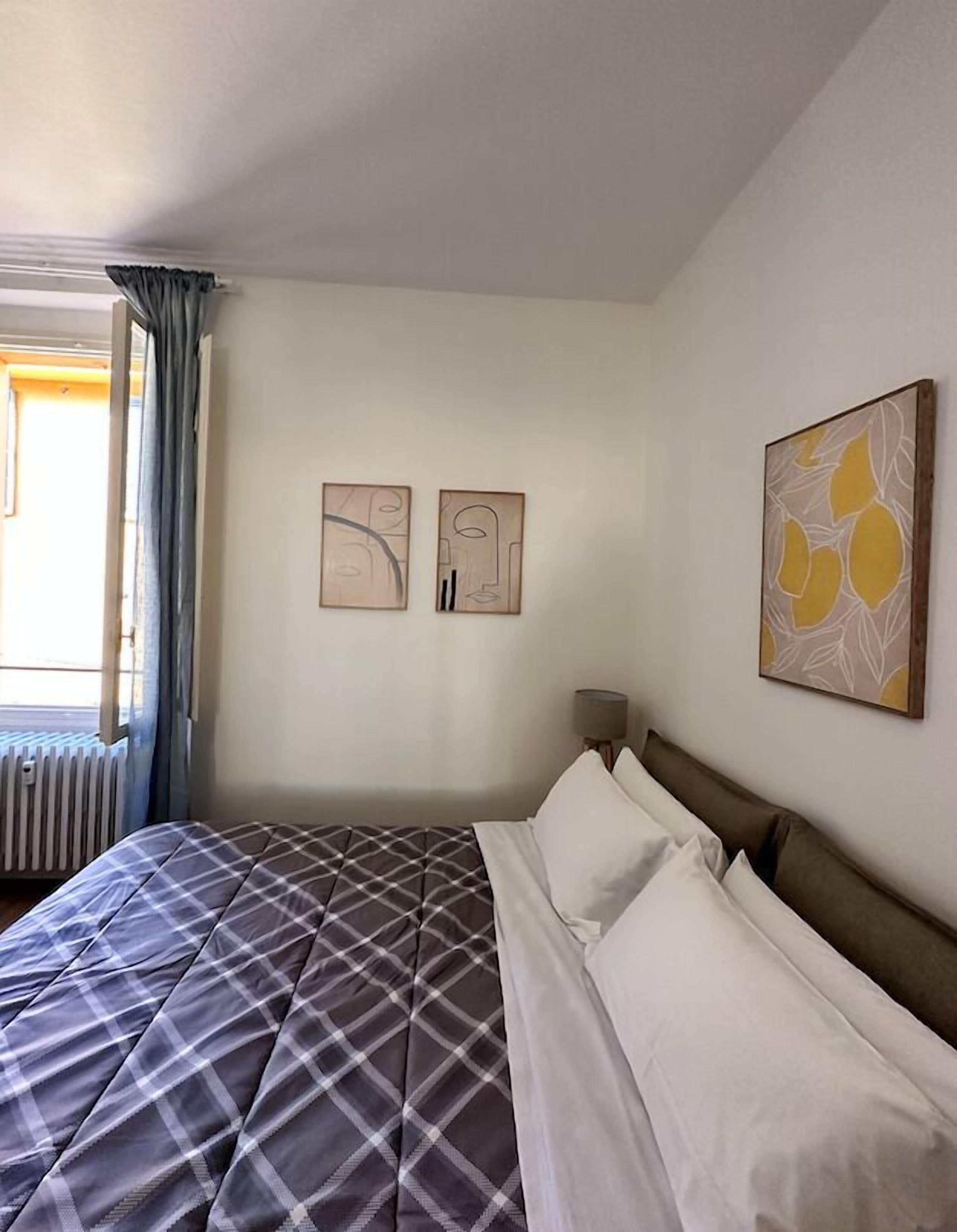 Una habitación de hotel con una cama grande, un radiador y tres obras de arte colgadas en la pared.