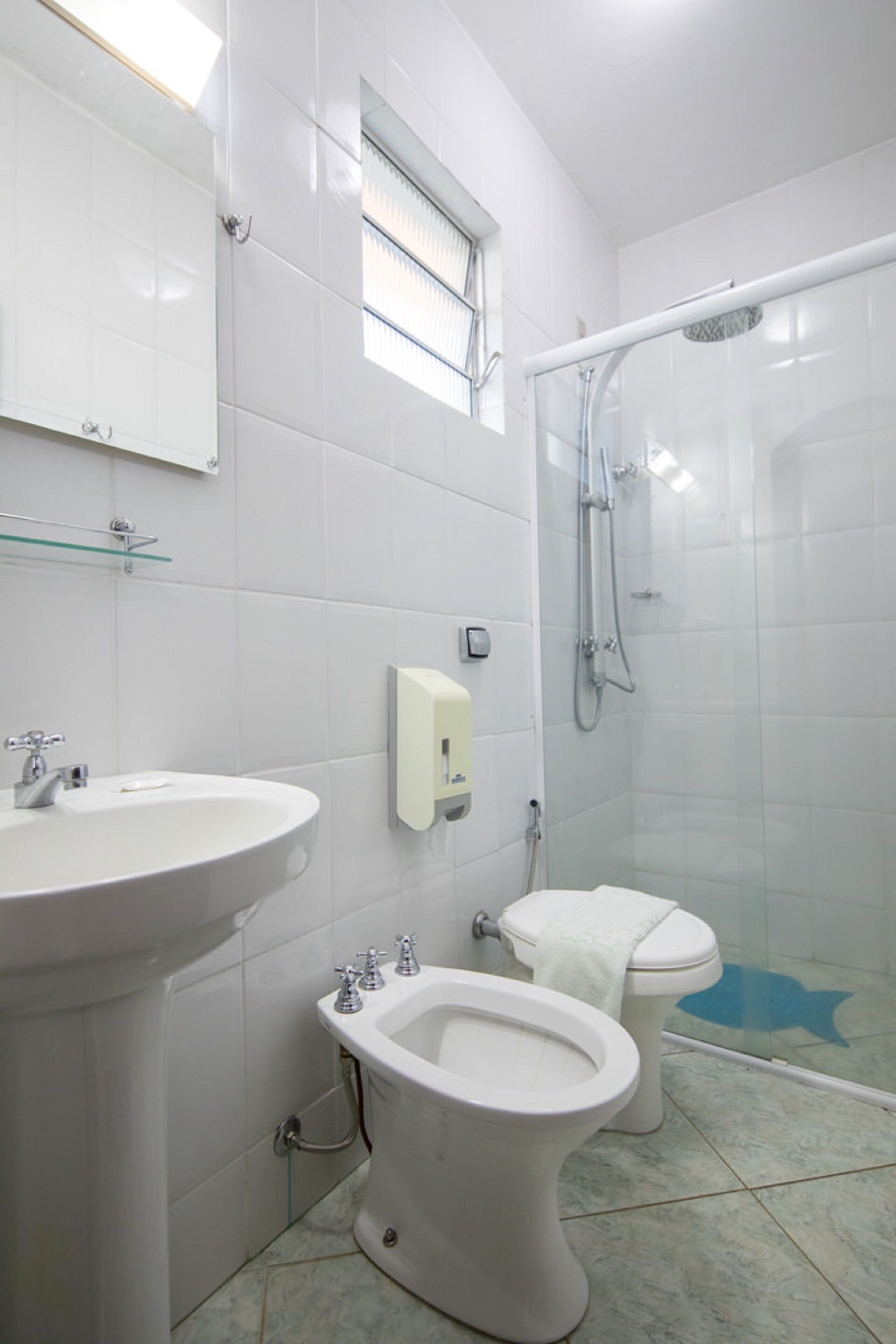 A bathroom with a sink, toilet, bidet, and shower.