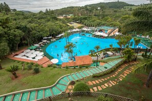 A large swimming pool surrounded by palm trees and a lush green landscape. - Parque Hotel Pimonte (São Francisco de Paula)
