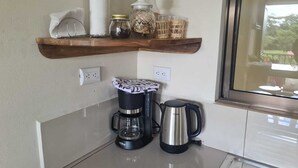 A kitchen with a coffee maker, a kettle, and a shelf with jars and a decorative item. - New apartment 5 minutes from the central park (La Fortuna)