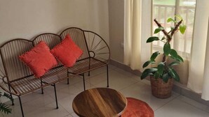 A living room with a metal sofa, a wooden coffee table, a red rug, a potted plant, and a colorful abstract painting on the wall. - New apartment 5 minutes from the central park (La Fortuna)