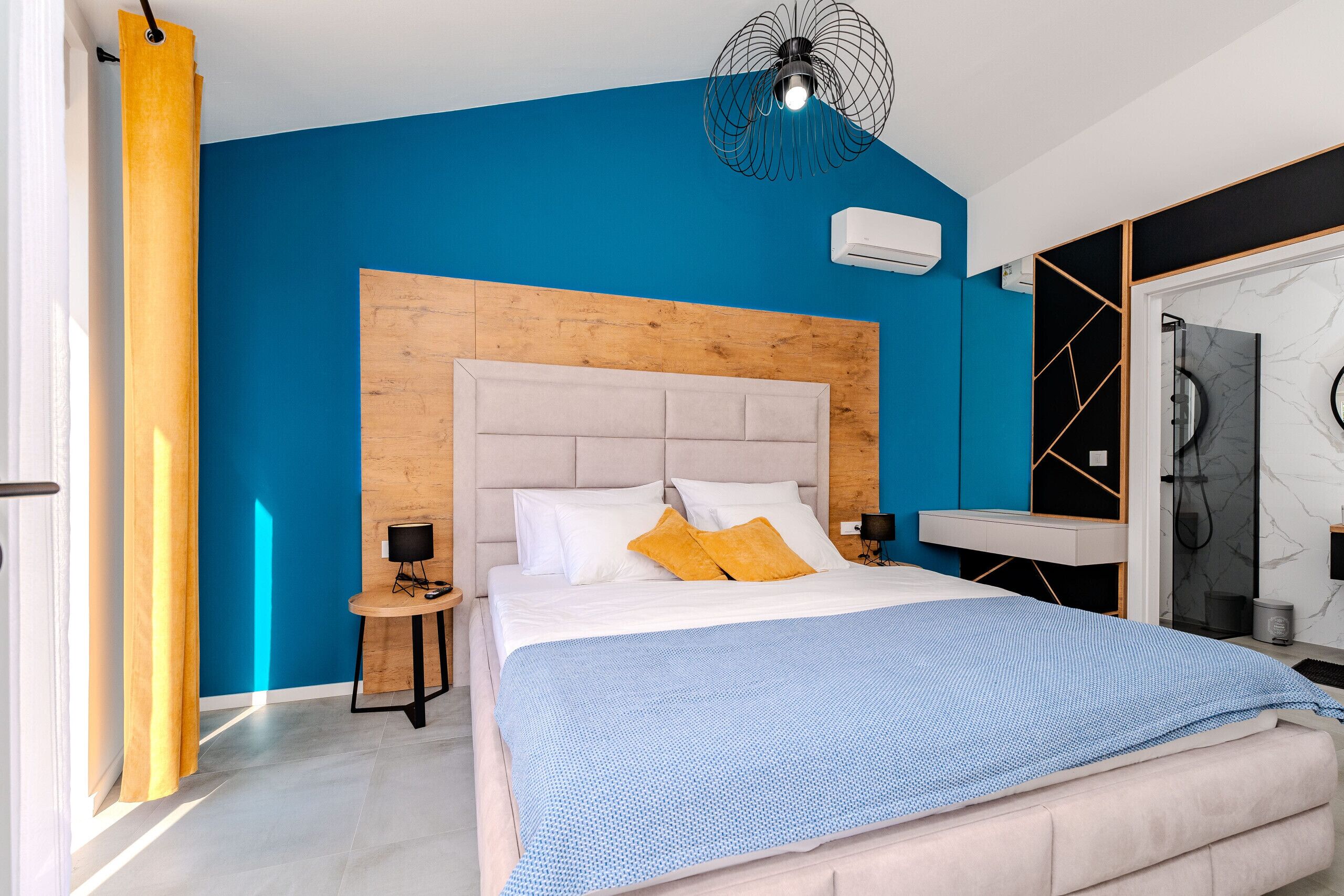 Een moderne slaapkamer met een groot bed, een houten hoofdbord, een nachtkastje en een ingebouwde bank.