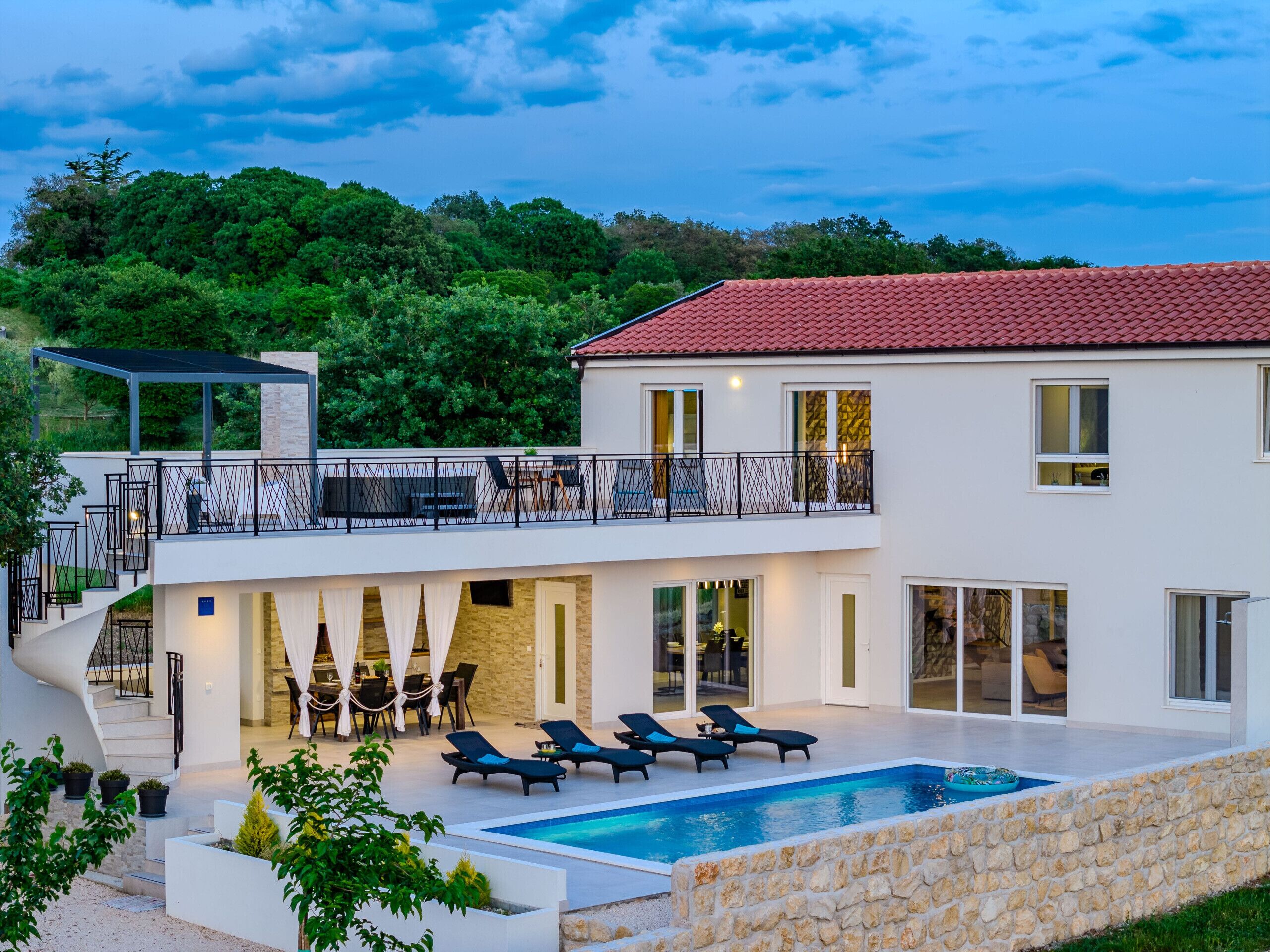 A modern two-story house with a swimming pool, outdoor seating, and a balcony.