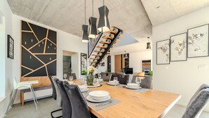 A modern dining area with a wooden table set for six, black chairs, and a black and white abstract wall art piece.