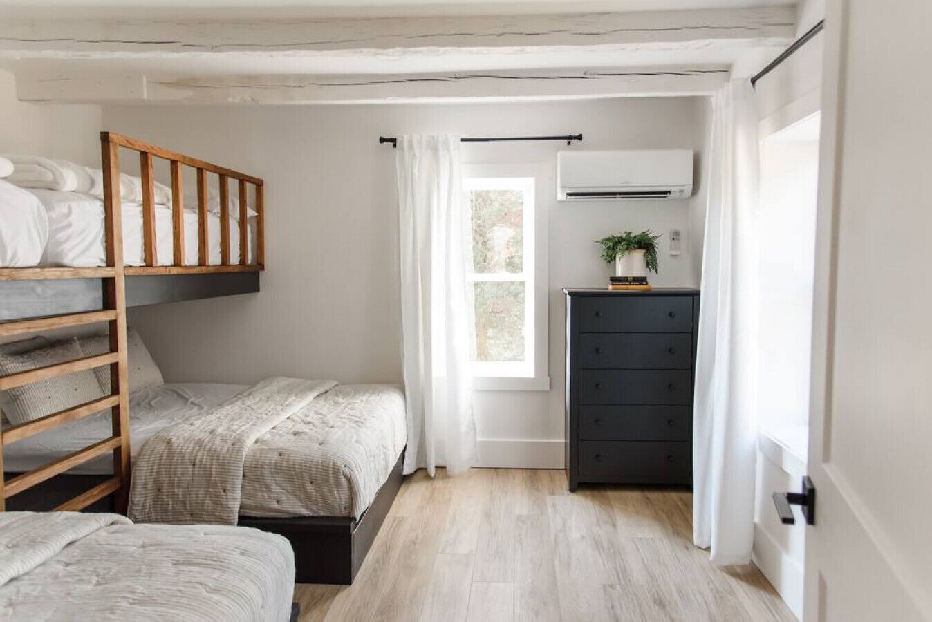 Une chambre avec deux lits, une commode, un climatiseur et une fenêtre avec des rideaux.