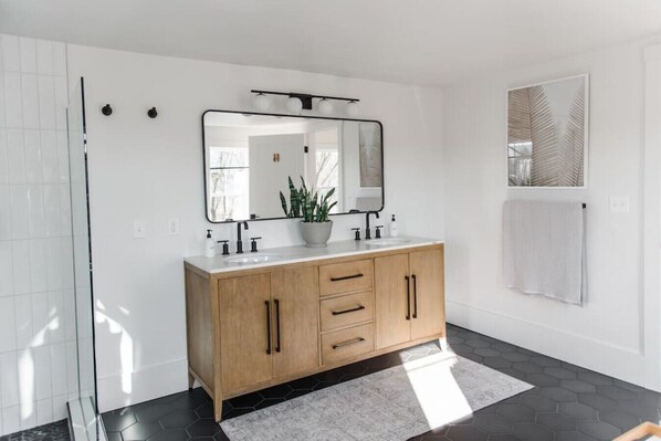 A modern bathroom with a wooden vanity, a large mirror, and a potted plant.