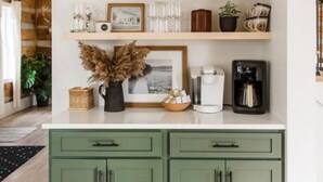 A kitchen with green cabinets, a coffee machine, and various decorative items on shelves. - Secluded Valley Oasis with Swimming Pond, Spa, Firepit, 3BD/2BA, Family friendly (Liverpool)