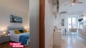 Moderni hotellihuone, jossa on sänky, yöpöytä ja taulu seinällä.