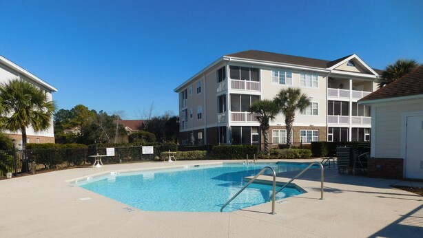A swimming pool with a metal ladder, surrounded by a concrete deck. - Wedgewood 324 - Cute Condo! (North Myrtle Beach)