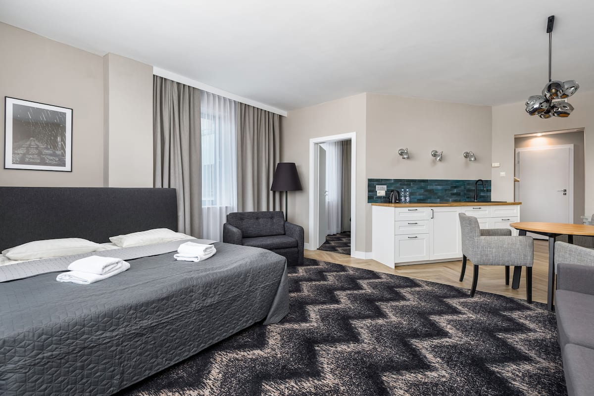 Een hotelkamer met een bed, een bureau, een stoel, een kitchenette en een badkamer.