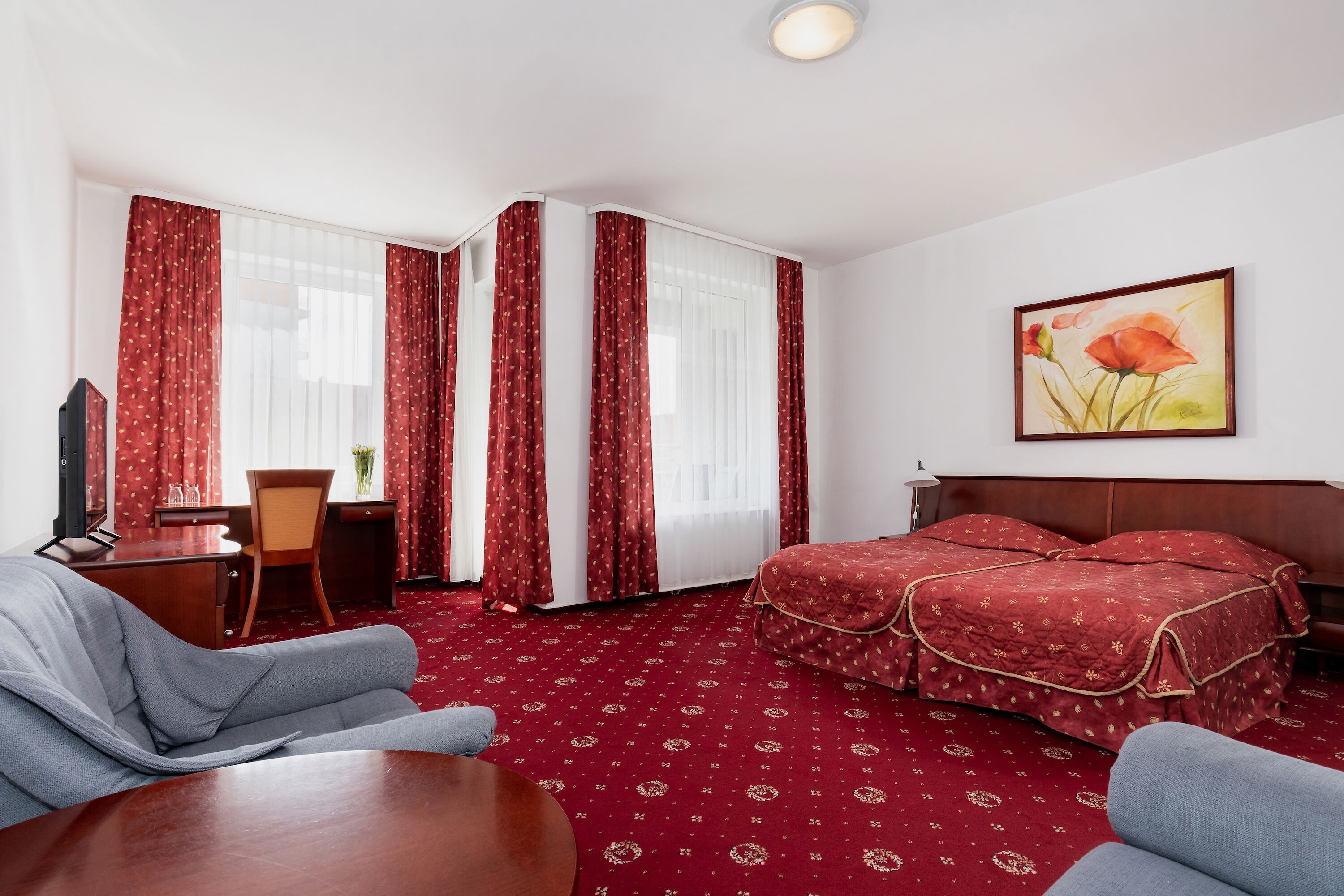 Une chambre d’hôtel avec un lit, un bureau, une chaise et un téléviseur.