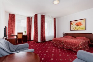 Una habitación de hotel con una cama, un escritorio, una silla y un televisor.