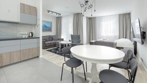 Une chambre d’hôtel moderne dotée d’une cuisine, d’un coin repas et d’une grande fenêtre avec des rideaux.