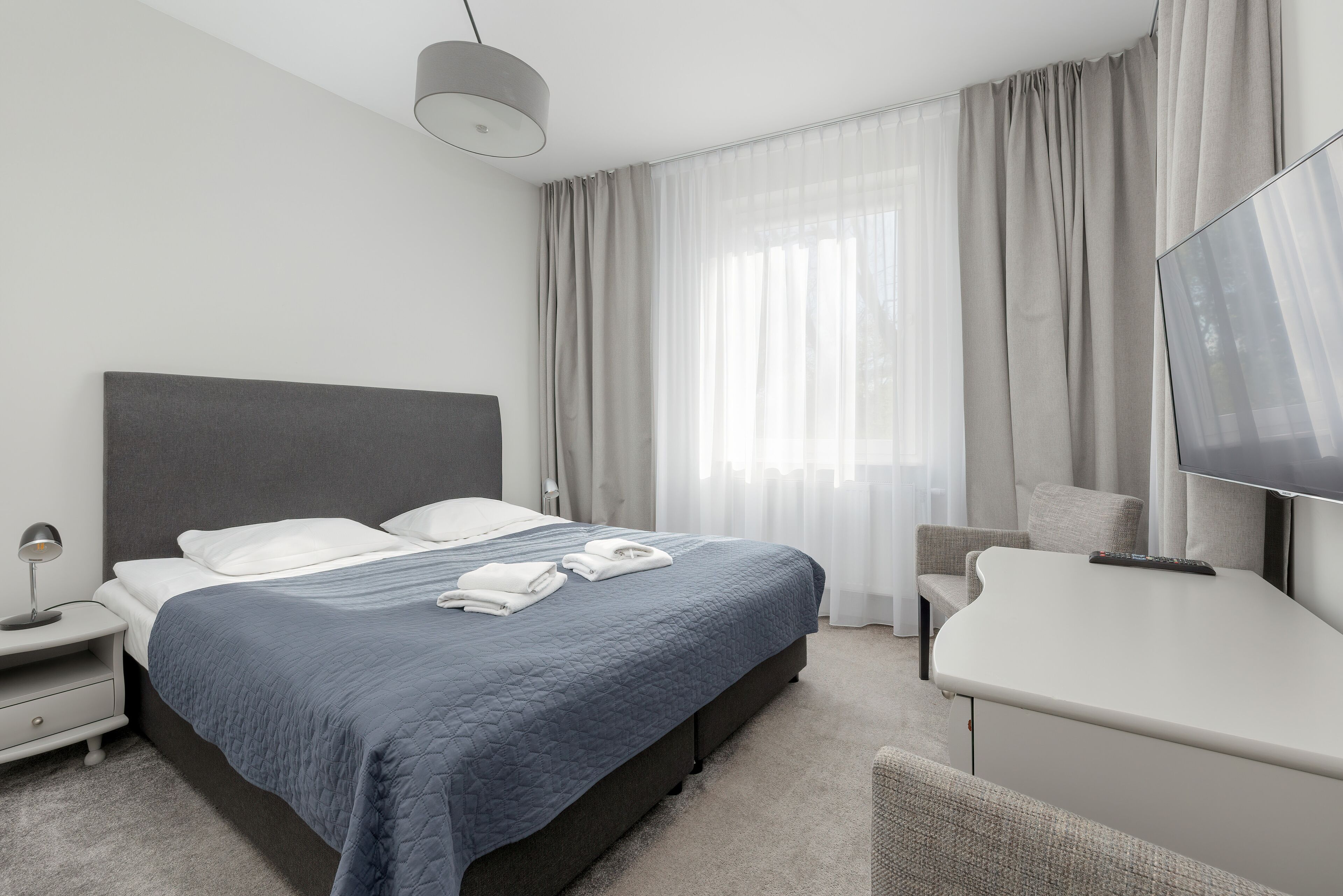 Une chambre d’hôtel moderne, dotée d’un grand lit, d’un bureau et d’une télévision.