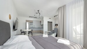 Une chambre d’hôtel moderne, dotée d’un grand lit, d’un bureau, d’une chaise, d’un miroir et offrant une vue sur l’extérieur.