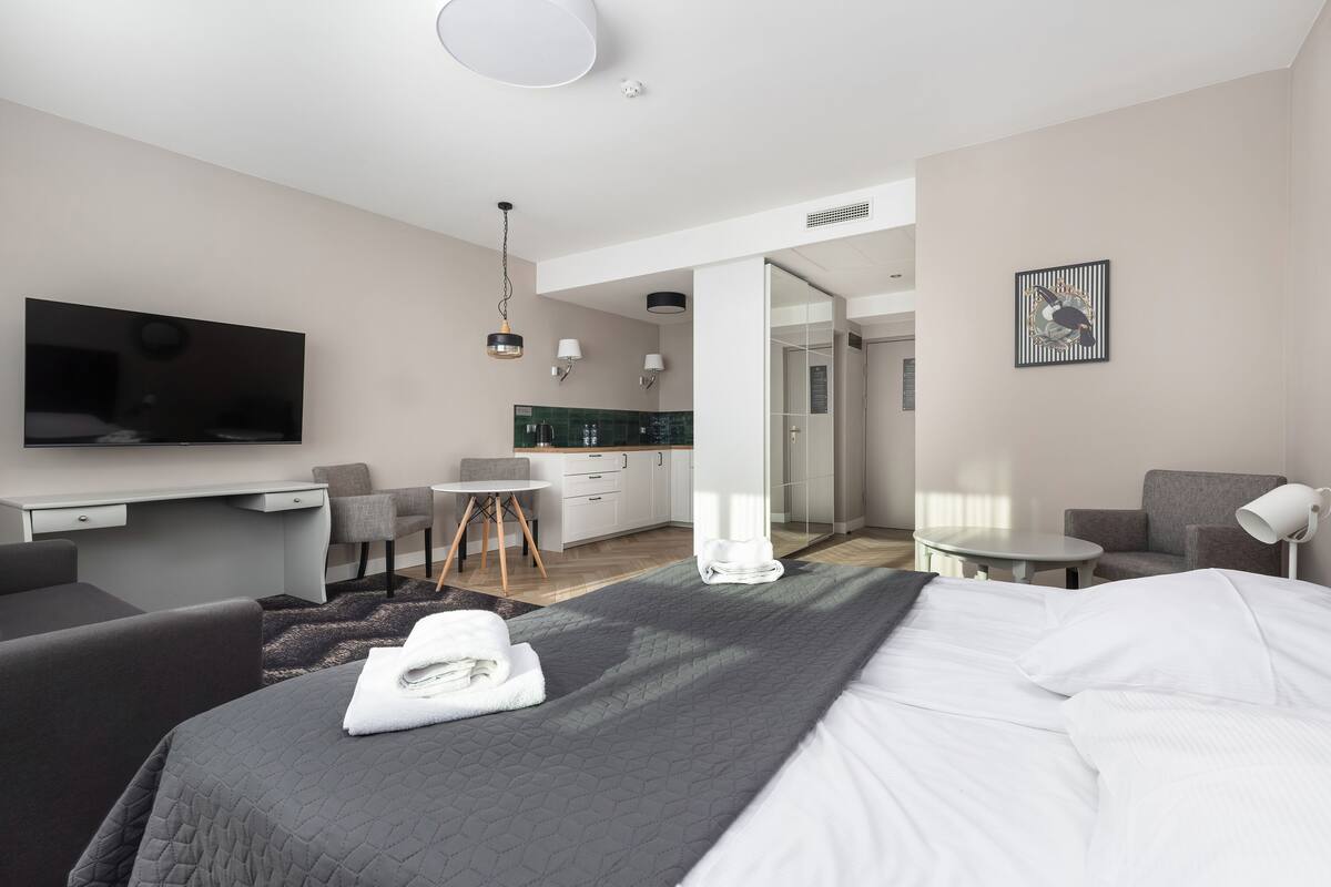 Een moderne hotelkamer met een groot bed, een bureau, een stoel, een tafeltje en een televisie.