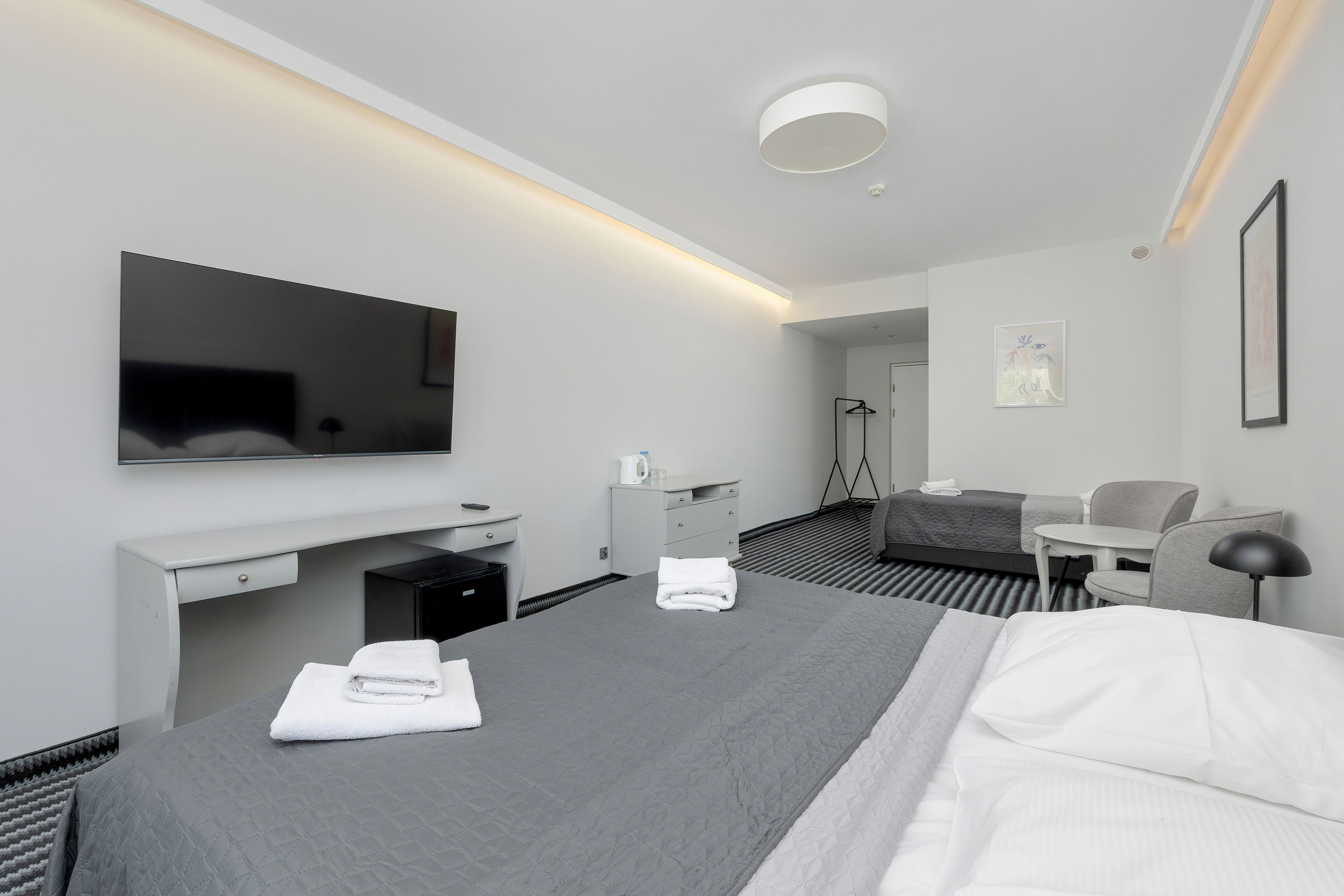 Una habitación de hotel moderna con una cama grande, un escritorio, una silla, un televisor y una mesita.