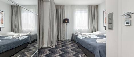 Habitación de hotel con dos camas, un espejo grande, una lámpara de pie y una alfombra estampada.