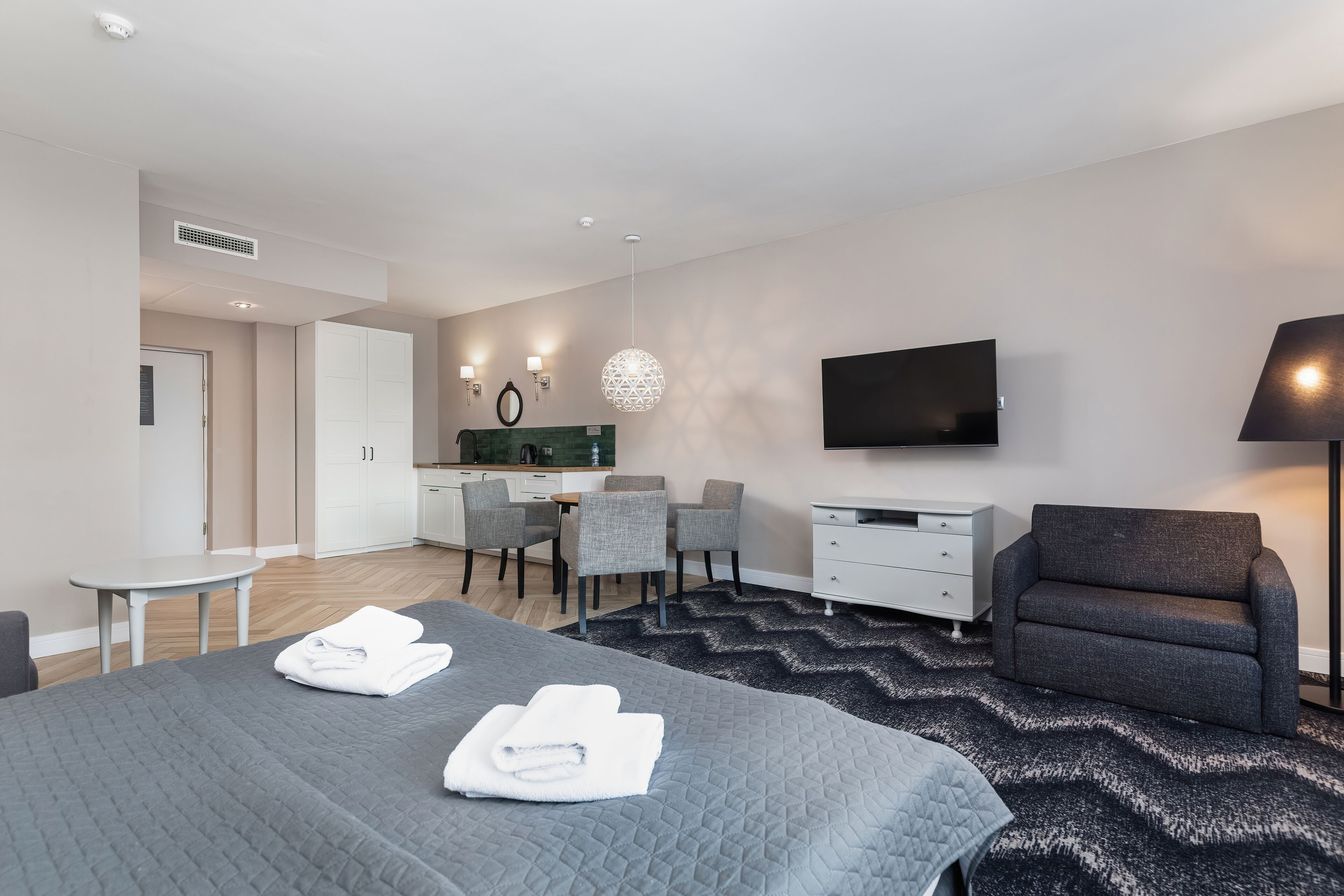 Een moderne hotelkamer met een bed, een bureau, een stoel, een televisie en een lamp.