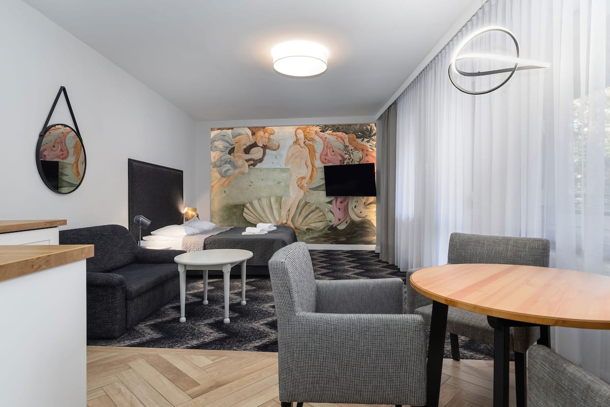 Een moderne woonkamer met een bank, een ronde houten tafel en een aan de muur bevestigde televisie.