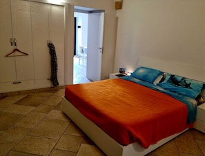 A bedroom with a bed, a wardrobe, and a door leading to a balcony.