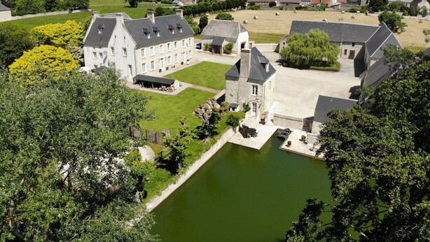 Un vaste domaine comprenant plusieurs bâtiments, une cour centrale et un étang.