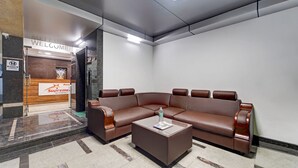 A reception area with a brown leather sofa, a coffee table, and a reception desk. - Treebo Era City Stay (Chennai)