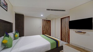 A modern hotel room with a large bed, a flat-screen TV mounted on the wall, and a wooden door. - Treebo Era City Stay (Chennai)