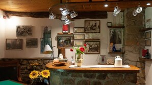 A rustic interior with a stone counter, framed pictures, and a wooden ceiling. - Villa con Piscina - Casale Rancaccio (Arezzo)