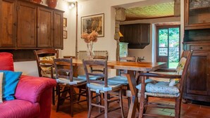 A rustic dining area with wooden furniture, a stone wall, and a window with a view of greenery. - Villa con Piscina - Casale Rancaccio (Arezzo)