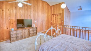A bedroom with wooden walls, a bed with a metal headboard, a dresser, a ceiling fan, and a window with a view. - Jo Jo's House - Off-Ocean, Dog Friendly (Pawleys Island)