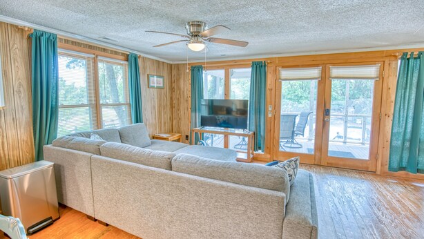 A living room with a sectional sofa, a television, and a ceiling fan. - Jo Jo's House - Off-Ocean, Dog Friendly (Pawleys Island)