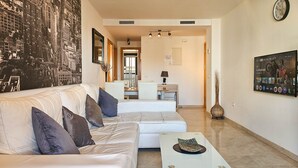 A modern living room with a white sofa, a coffee table, and a cityscape mural. - Calablanca walking distance to La Cala and beach (La Cala de Mijas)