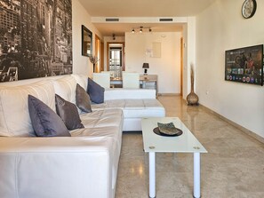 A modern living room with a white sofa, a coffee table, and a cityscape mural. - Calablanca walking distance to La Cala and beach (La Cala de Mijas)