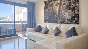 A modern living room with a white leather sofa, a glass coffee table, and a cityscape painting on the wall. - Calablanca walking distance to La Cala and beach (La Cala de Mijas)