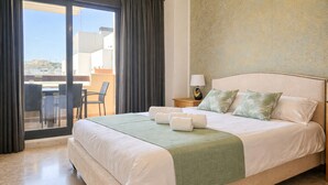 A hotel room with a bed, a small table with chairs, a nightstand, and a view through a glass door. - Calablanca walking distance to La Cala and beach (La Cala de Mijas)