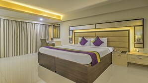 Une chambre d’hôtel moderne avec un grand lit, des tables de chevet, un bureau et un miroir.