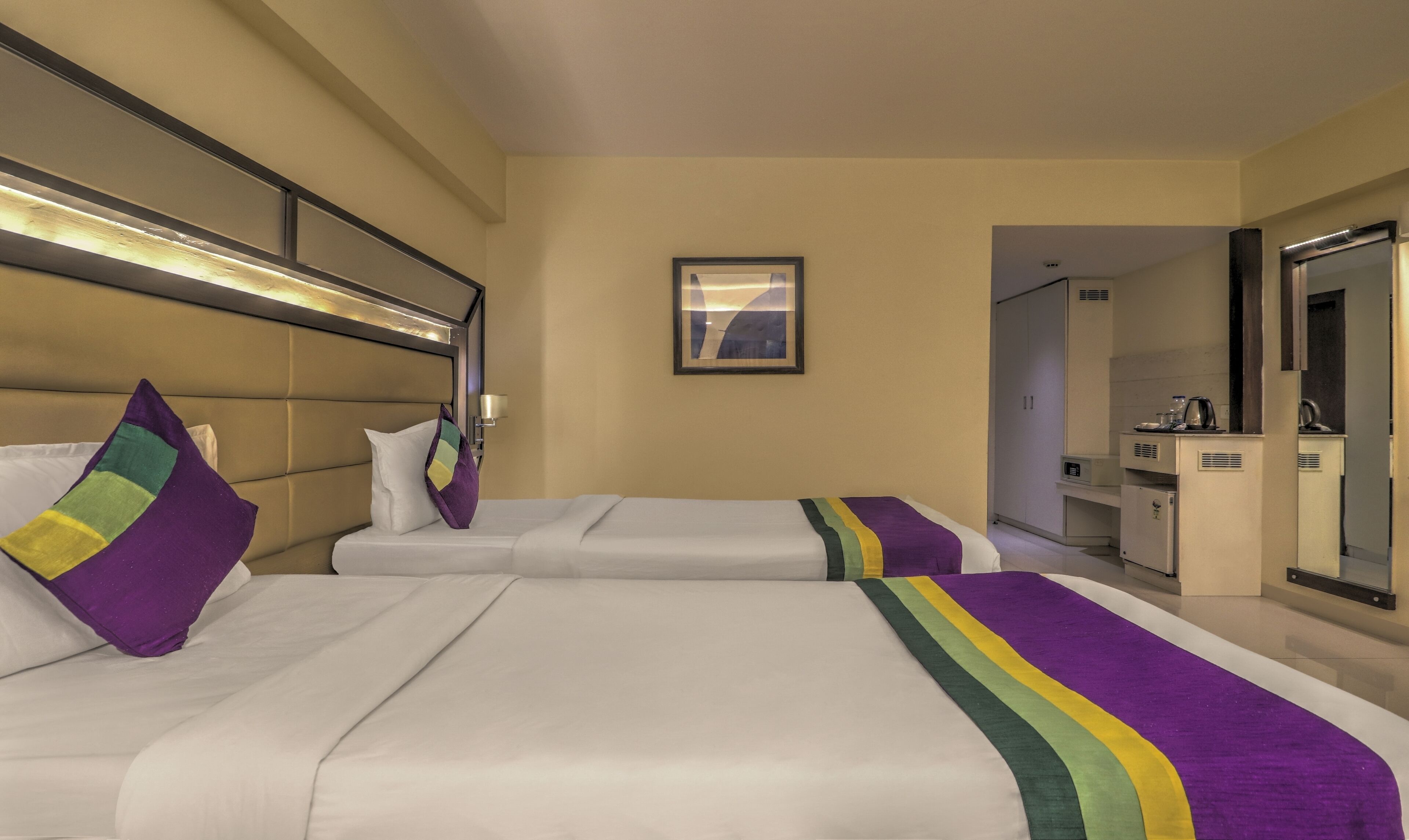 Ein Hotelzimmer mit zwei Betten, einem Badezimmer und einer Küchenzeile.