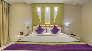 Habitación de hotel con una cama grande, dos mesitas de noche, cabecero con iluminación integrada y vistas a la ciudad.